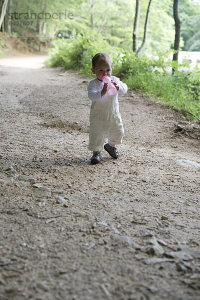 Baby Mädchen hält Babyflasche im Wald