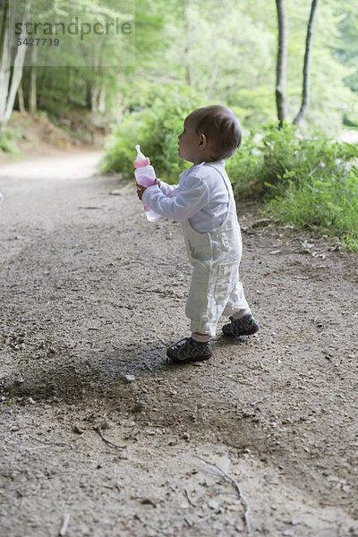 Baby Mädchen hält Babyflasche im Wald