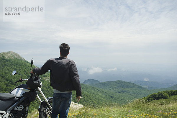 Mann beim Motorradfahren auf dem Berg  Rückansicht