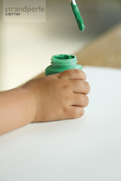 Kind taucht Pinsel in Farbe  abgeschnitten