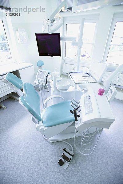 Blick in Behandlungszimmer mit Behandlungsstuhl und Konsole mit Spray und Winkelstücken in Zahnarztpraxis