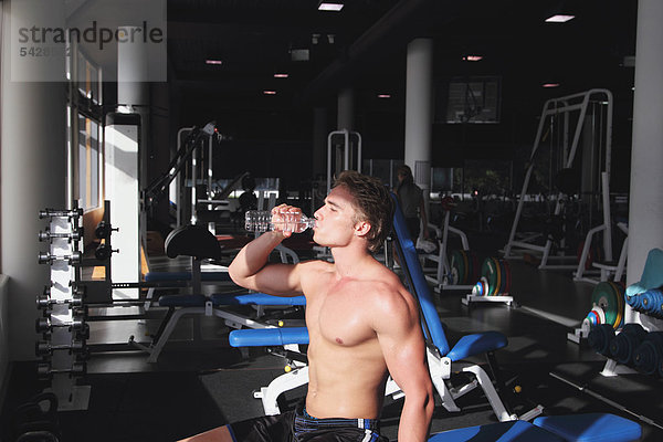 Junger Mann gekämpft Trinkwasser während des physischen Trainings in ein Fitness-Studio