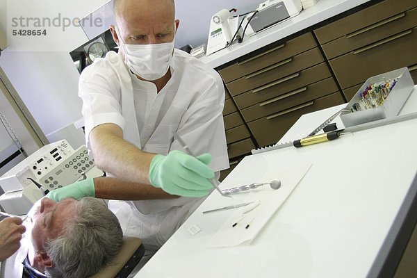 Zahnarzt greift mit Pinzette Papierspitze zum Trocknen des Wurzelkanals