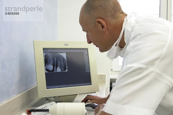 Arzt betrachtet Röntgenaufnahme auf Computermonitor