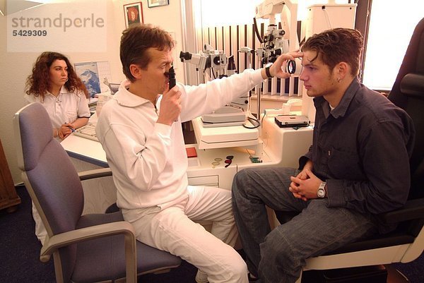 Augenarzt bei der Untersuchung bzw. Behandlung eines jungen Mannes
