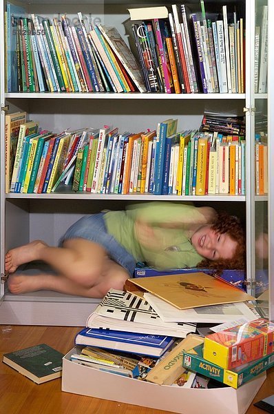 Mädchen liegt im einem Bücherregal - ADHS Syndrom