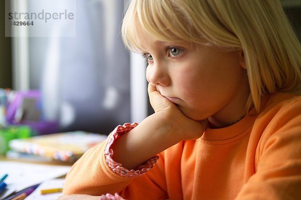 Mädchen sitzt traurig am Schreibtisch - ADHS Syndrom