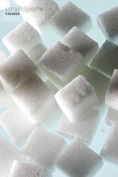 Zuckerwürfel gestapelt auf grünem Untergrund - Im Verdauungstrackt wird Zucker - Saccharose - in seine Bestandteile Fruktose und Glukose gespalten - neben diesen Energielieferanten enthält Zucker keinerlei Wirkstoffe