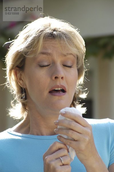 Frau im mittleren Alter niest