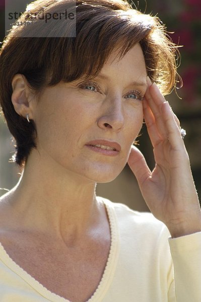 Portrait einer Frauen im mittleren Alter mit Kopfschmerzen