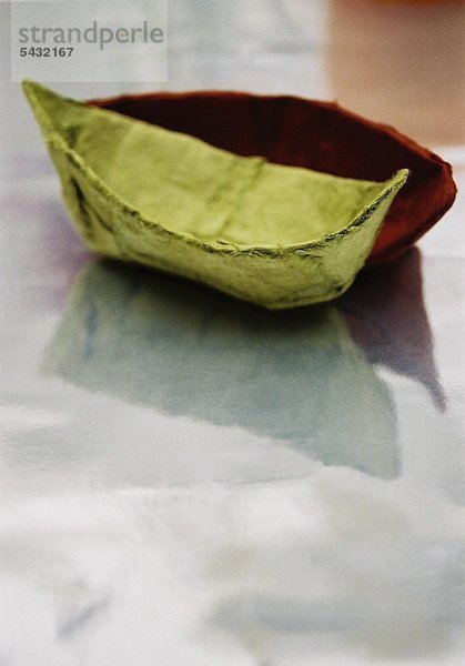 zwei kleine Papierboote auf glattem spiegelndem Grund