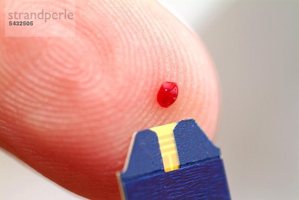 Roche Accu-Chek Aviva Blutzuckermeßgerät für den Patientengebrauch - Detail Bluttropfen auf Fingerkuppe und Teststreifen