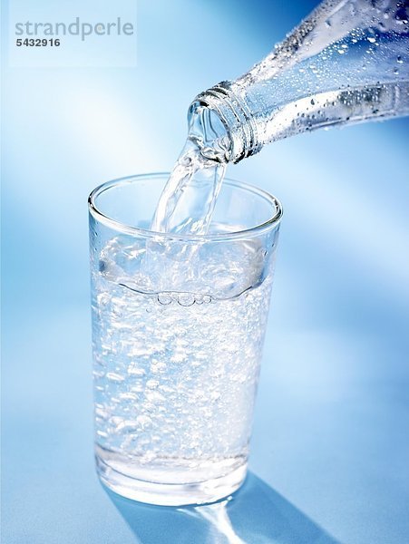 Wasser wird aus einer Flasche in ein Glas geschenkt - viele Luftblasen CO2 ( Wasser ) - H2O ( Kohlensäure )