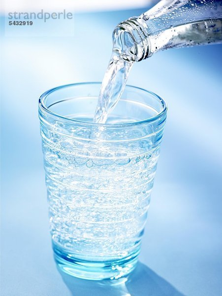 Wasser wird aus einer Flasche in ein Glas geschenkt - CO2 ( Wasser ) - H2O ( Kohlensäure )