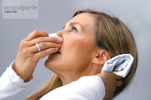 Frau mit Nasenbluten hält ihren Kopf zurück   Taschentuch an der Nase