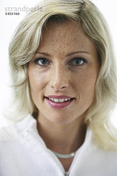 Portrait einer blonden Frau mit weißem Oberteil  Sommersprossen