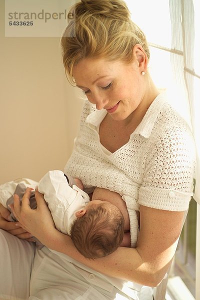 Eine Frau stillt ihr neugeborenes Kind