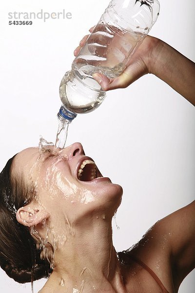 Eine lachende junge Frau gießt sich klares Wasser über Gesicht und Körper - woman - water - laughing mund
