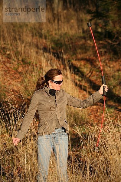 Frau mit Flexibar am Waldrand - Flexibar - Flexi-Bar - Der in Schwingung gebrachte Flexi-Bar bewirkt durch seine Vibration eine tiefgehende Reaktion des Körpers - reflektorische Anspannung des Rumpfes   effektiv gegen Rückenschmerzen - Zur Kräftigung der Tiefenmuskulatur   zur Kraftausdauer   zur Straffung des Bindegewebes   zur Verbesserung der Körperhaltung - Bodystyling