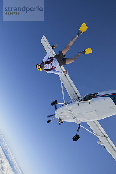 Fallschirmspringer mit Schwimmflossen und Taucherbrille in der Luft