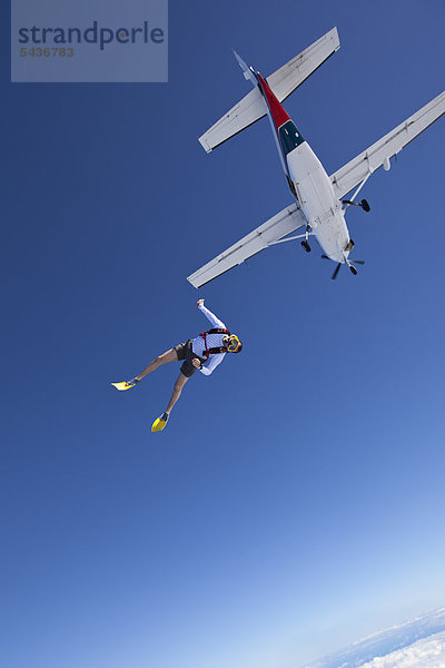 Fallschirmspringer mit Schwimmflossen und Taucherbrille in der Luft