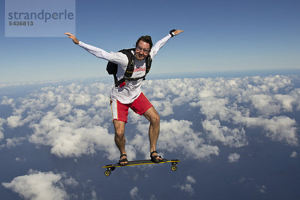 Fallschirmspringer mit Skateboard in der Luft