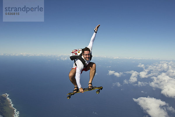 Fallschirmspringer mit Skateboard in der Luft