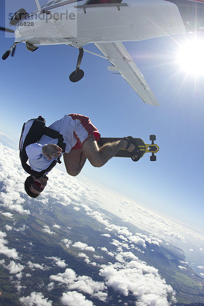Fallschirmspringer mit Skateboard in der Luft