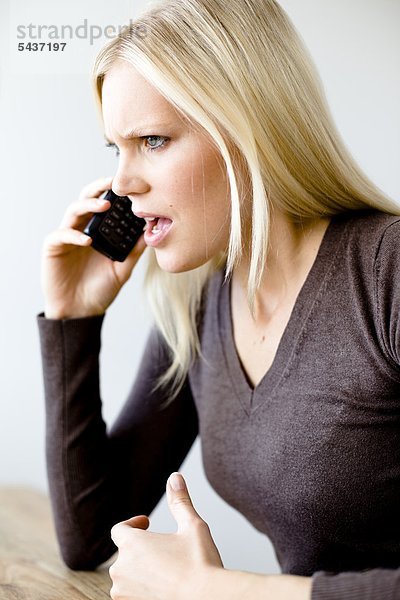 Wütende blonde Frau telefoniert