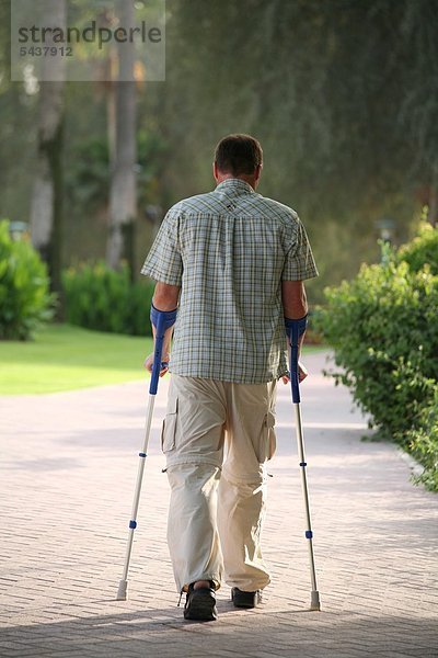 Mann mit Krücken von hinten - man with crutches - backview ]