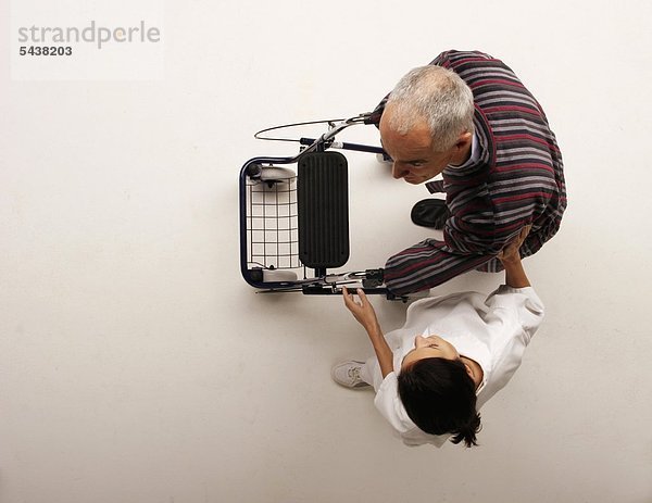 Altenpflegerin begleitet alten Mann mit Gehhilfe