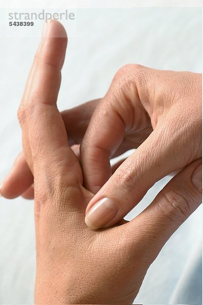 Nahdetail - Junge Frau massiert die Haut zwischen Daumen und Zeigefinger - Finger Akupressur