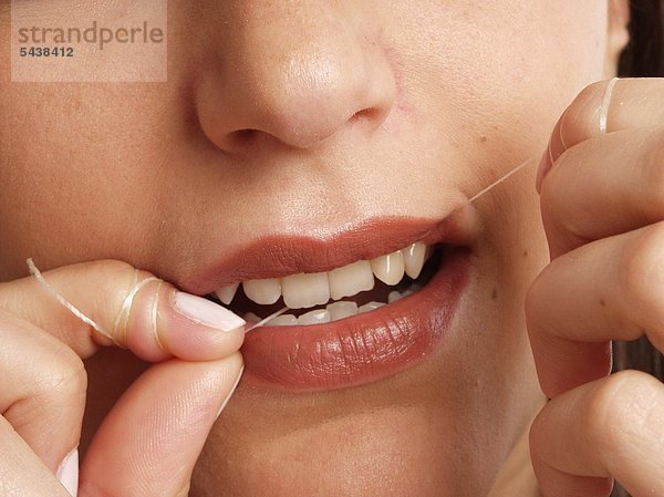 Frau  20-25 Jahre alt reinigt sich mit Zahnseide die Zähne mund