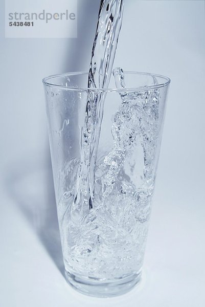 Wasserschwall fliesst in ein Glas  Bewegung eingefroren