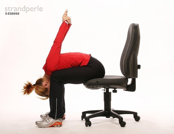 fit im Büro - junge Frau sitzt auf Bürostuhl und macht Gymnastik - Oberkörper auf Oberschenkel und Arme nach hinten oben nehmen - Beweglichkeit