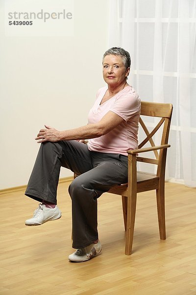 ältere Frau macht Gymnastik auf Stuhl - Bauchmuskeln aktiv - Muskelkraft - Seniorin