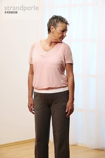 ältere Frau macht Dehnübung für den Nacken und Hals - Kopf drehen - Dehnen - Beweglichkeit - Seniorin