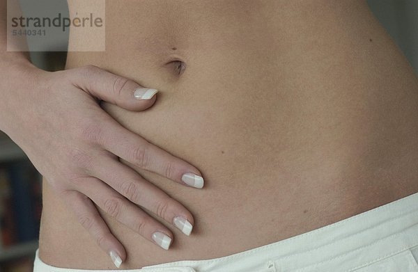 Nah Detail - flacher Bauch mit schlanker Hand von einer jungen gepflegten Frau