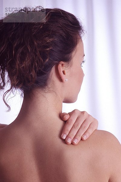 Rückenansicht - Junge Frau hält eine Hand an ihre Schulter