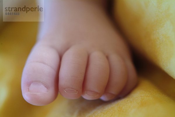 Close Up eines Neugeborenenfußes vor gelbem Hintergrund