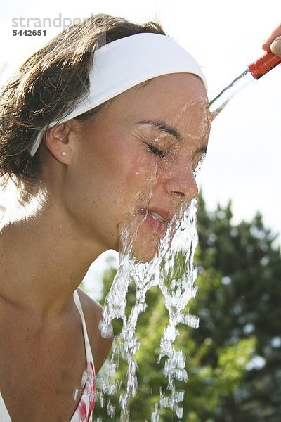 Kalter Gesichtsguss nach Kneipp - Bei einer jungen Frau wird das Gesicht mit kaltem Wasser abgegossen