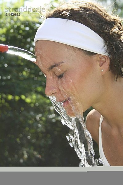 Kalter Gesichtsguss nach Kneipp - Bei einer jungen Frau wird das Gesicht mit kaltem Wasser abgegossen