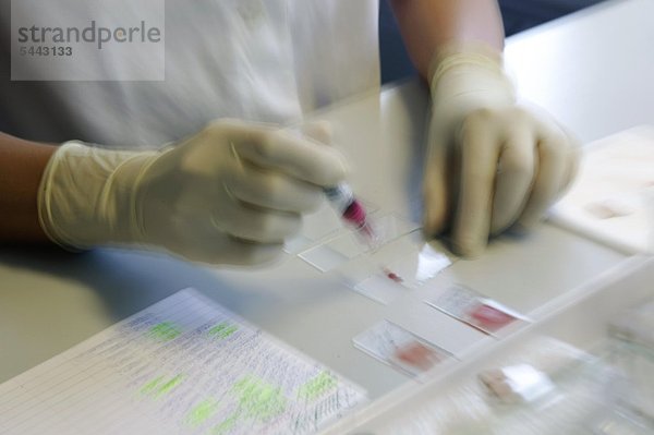 In einem modernen Kliniklabor werden von einer Laborantin verschiedene Blutproben analysiert
