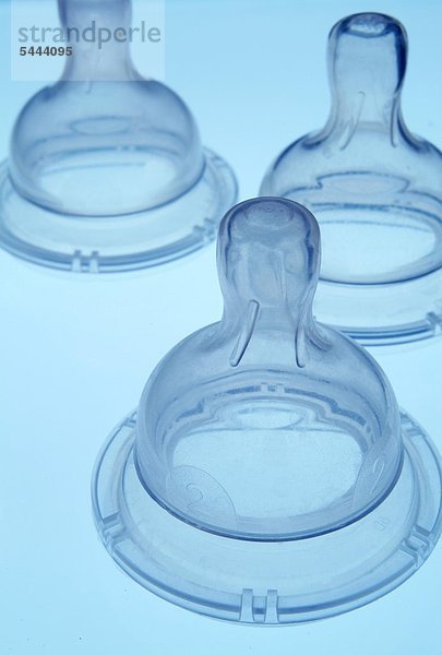 Drei Sauger für Babyfläschchen auf blauem Grund  close up