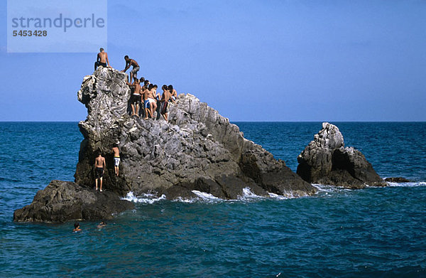 Eine Gruppe von Männern auf einem Felsen im Meer.