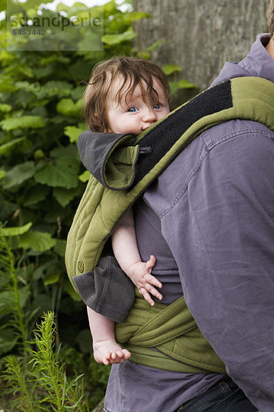 Ein Vater trägt seine Tochter im Tragesitz  Schwerpunkt Baby