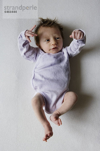 Ein Neugeborenes schaut auf ihre Hand.