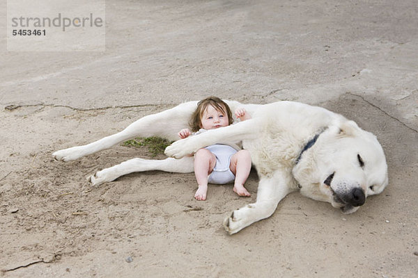 Ein Baby liegend mit einem Hund