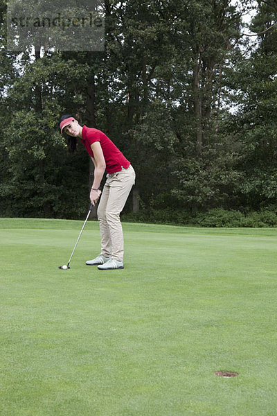 Eine Golferin  die sich auf das Putten vorbereitet.