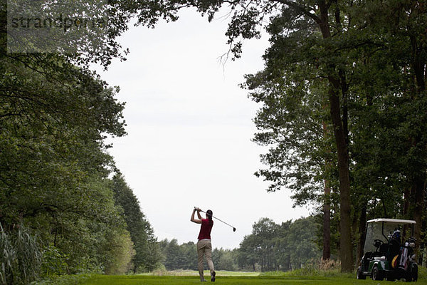 Eine Golfspielerin beim Abschlag  Rückansicht